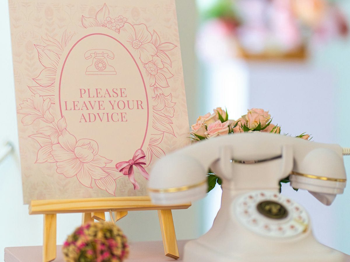 A vintage cream telephone beside a sign asking guests to leave their advice